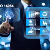 Photograph of a person in a suit interacting with a futuristic digital interface displaying ISO 14064 standards related to carbon dioxide (CO2) reduction.