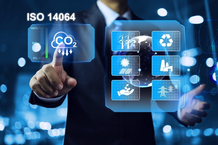Photograph of a person in a suit interacting with a futuristic digital interface displaying ISO 14064 standards related to carbon dioxide (CO2) reduction.