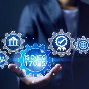 Photograph of a person holding floating blue and silver gear icons representing ISO/IEC 17025 standard and related concepts.