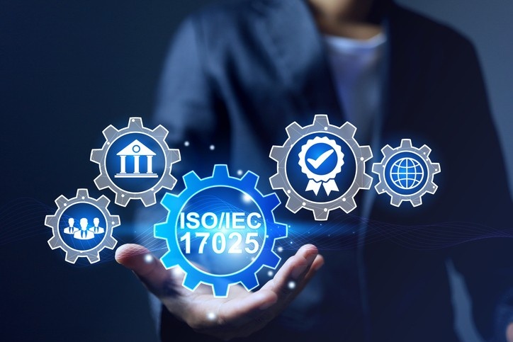 Photograph of a person holding floating blue and silver gear icons representing ISO/IEC 17025 standard and related concepts.